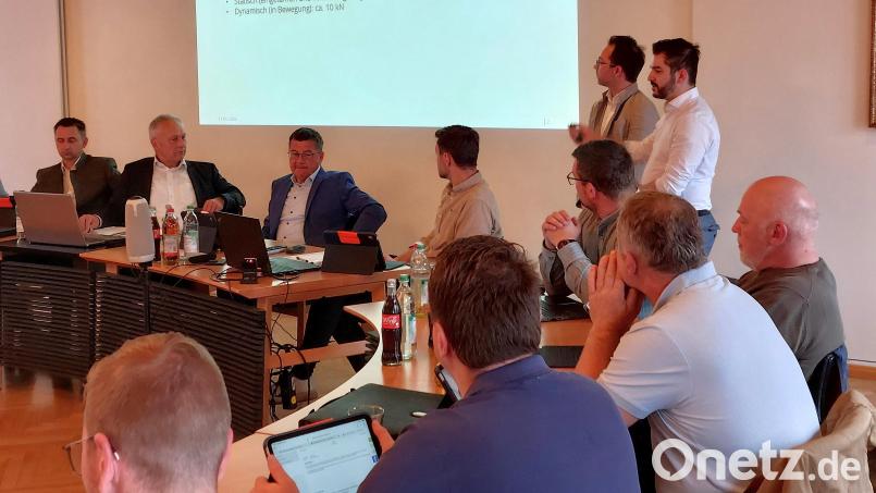 Florian Füger (stehend, links) von der Firma Harth & Flierl Architekten sowie Tobias König (stehend, rechts) von der Ursensollener Firma Ames Wiring stellten Technik und Ausführung der versenkbaren Bühne vor, die im Rahmen des Ausbaus der Ganztagsbetreuung der Grund- und Mittelschule Vilseck in der Mehrzweckhalle installiert werden soll. Bild: mfh