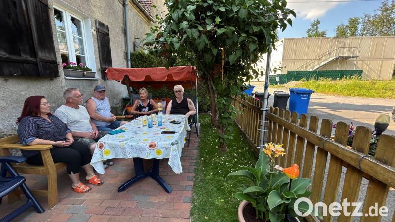 Einige Anwohner des Containerdorfs (rechts im Hintergrund) in Neustadt/WN treffen sich im Vorgarten von Familie Mastalar. Die Modulanlage wird derzeit abgebaut. Die Geflüchteten sind bereits ausgezogen. Bild: ck