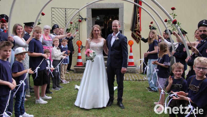 Freudstrahlend durchschreiten Carolin und Christoph Dietrich das Ehrenspalier der Feuerwehr Pfaffenreuth. Bild: Konrad Rosner