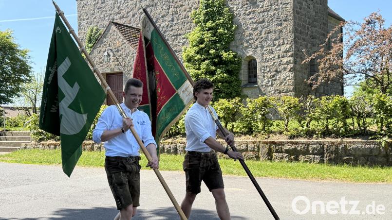 Thomas Schmid trägt das grüne KLJB - Banner und Jonas Feiler (rechts) die alte Lennesriether Burschenvereinsfahne vor die Albersriether Dorfkapelle. Bild: fvo