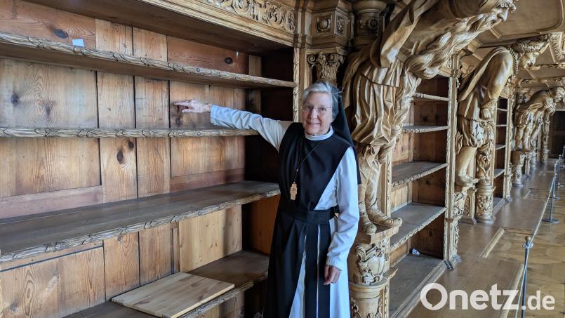 In der Stiftsbibliothek zeigt Äbtissin M. Laetitia Fech auf einen der roten Punkte auf den Rückwänden der leeren Bücherregale. Damit sind besonders schadhafte Stellen markiert. Bild: pz