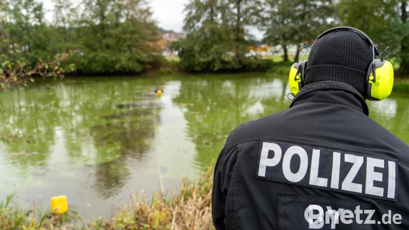 Ein Polizist trägt ein gelb-schwarzes Headset auf dem Kopf. Mit diesem kommuniziert er mit seinem Kollegen, der sich im Wasser befindet. Im Oktober wurde ein Weiher in Wernberg-Köblitz abgesucht. Archivbild: sbö