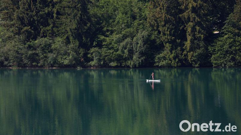 Eine Frau paddelt auf einem Stand-up-Paddle-Board über den Forggensee. Bild: Karl-Josef Hildenbrand/dpa