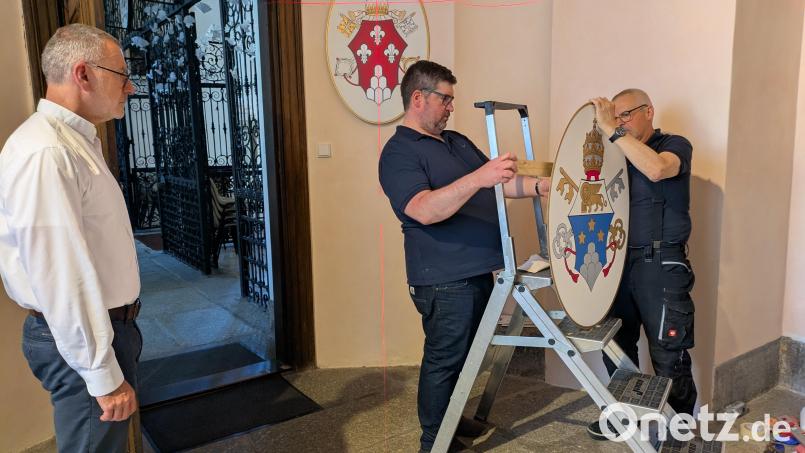 Beim rechten Seiteneingang zur Basilika wurde ein geeigneter Raum für die Papstwappen-Galerie gefunden. Von links Pfarrer Dr. Thomas Vogl zusammen mit Mesner Dominik Sirtl und Johann Schnur, die die Wappen am Freitag zusammen mit Hubert Heinzl aufhängten. Bild: Paul Zrenner