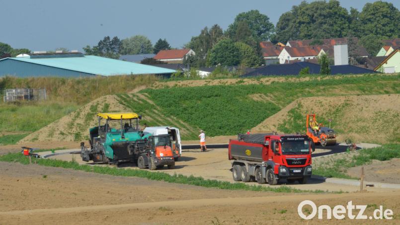 Derzeit führen die Straßenbauer des Subunternehmens Firma Huber, Inhaber Josef Rappl GmbH & Co. KG die letzten Asphaltierungsarbeiten durch. Zum Baugebiet "Sommerwiesen" hin wurde ein Lärmschutzwall errichtet. Bild: Elisabeth Dobmayer