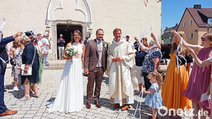 Durch ein langes Spalier schritten Sophia Wollner und Michael Schels nach der Trauungszeremonie. Mit im Bild ist Pfarrer Gregor Schweizer. Bild: Oswald Zintl
