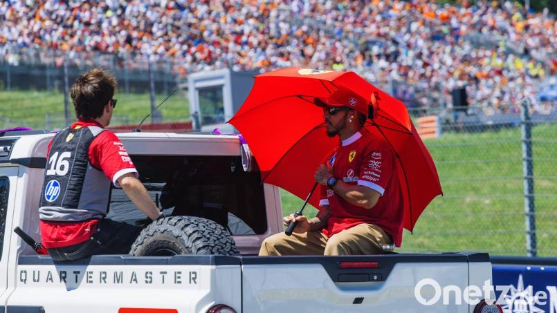 Die Ferrari-Fahrer Charles Leclerc (links) und Lewis Hamilton schützen sich im Vorjahr mit einem Schirm und einer Kühlweste vor der Hitze. Auch am Wochenende wird es in Spielberg heiß. (Archivbild) Bild: Philipp von Ditfurth/dpa