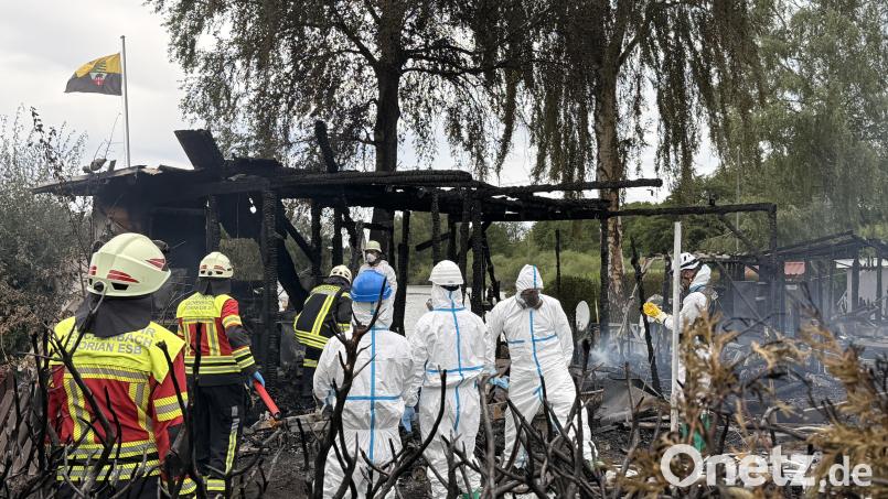 Feuerwehrleute und ein Team zur Spurensicherung begehen den Brandort beim Eschenbacher Rußweiher. Dort ist am Dienstagmorgen auf einem Campingplatz ein Feuer ausgebrochen. Eine Person starb. Bild: Gabi Schönberger