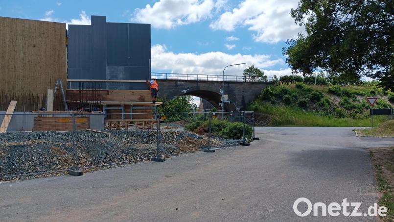 Noch steht die Gewölbebrücke in der Hauptstraße in Vorbach, während Arbeiter daneben auf dem Gelände des Sportplatzes den Nachfolgebau montieren. Die Durchfahrt unter der Bahnlinie ist ab Montag halbseitig und dann in zwei Etappen für mehrere Wochen komplett gesperrt. Bild: Alexander Goller