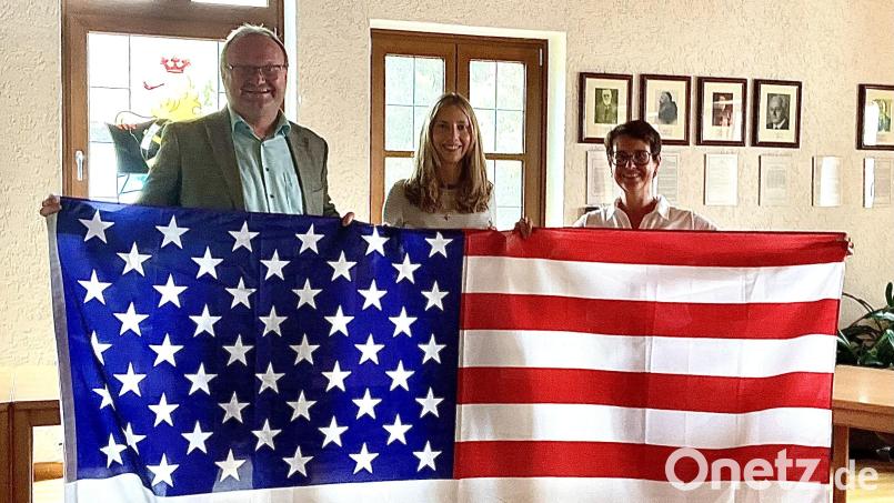 Die Juniorbotschafterin Paula Dotzler (Bildmitte) mit Bürgermeister Uwe König und Bundestagsabgeordneter Susanne Hierl zeigen mit der Flagge der USA an, wo es für Paula hingeht Bild: Gerhard Krones