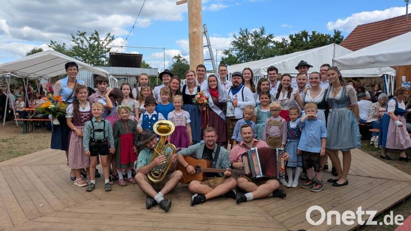 Bei der 14. Steiningloher Stodlkirwa tanzten 18 Kinder und sieben Kirwapaare um den 30 Meter hohen Kirwabaum. Als Oberkirwapaar wurden Sophia Pfab und Jonas Weiß (Bildmitte mit Blumenstrauß bzw. Kirwaliesl) ermittelt. Links hinten: Tanzlehrerin Eva Pfab, die seit zehn Jahren die Tänze einstudiert. Vorne das Trio „D’Allerscheynst’n“, das beim Austanzen aufgespielt hat. Bild: Christian Summer