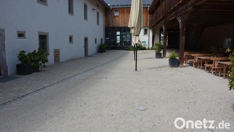 Links der befestigte Zugang zum Museum im Hintergrund, rechts der Sandboden, der nach Meinung von Reinhard Wurm ebenfalls befestigt werden sollte: Sand wird oft in die Räumlichkeiten getragen. Der Bürgermeister sucht dazu das Gespräch mit der Denkmalschutzbehörde. Bild: Josef Rosner