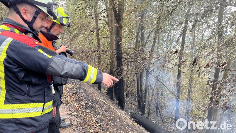 Christian Lorenz von der Staatlichen Feuerwehrschule Regensburg und Roland Wiesnet von der Freudenberger Feuerwehr zeigen am Steilhang des Freudenberger Johannisbergs, wo es noch raucht und glimmt im Boden. Bild: Heike Unger