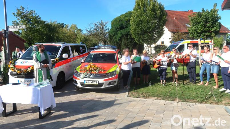 Diakon Tim Saborowski (links) segnete die neue Fahrzeughalle am Vilsecker Schwimmbad sowie die neuen Einsatzfahrzeuge für Wasserwacht und der Helfer vor Ort. Die Gruppe „Klangverwandt“ (rechts) gestaltete die kirchliche Feier mit passenden Liedern. Bild: Rosi Hasenstab
