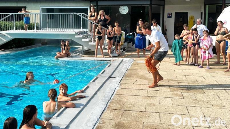 Demonstration beim diesjährigen Freibadfest: ein Mitglied der Wasserwacht am Beckenrand, mit einer langen Leine in der Hand, rettet mit Hilfe eines Wurfsacks einen erschöpften Schwimmer. Bild: Norbert Weis