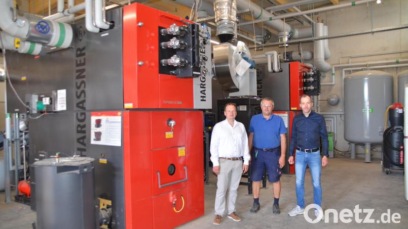 Bürgermeister Christian Porsch, Gemeindemitarbeiter Roland Steininger sowie Kewog-Geschäftsführer Rainer Hecht (von links) stehen in der Heizhalle des neuen -zentrums mit den beiden Industrie-Hackschnitzelöfen. Bild: Arnold Koch