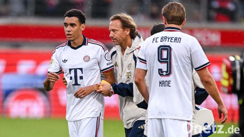 Jamal Musiala verlässt nach seinem Zusammenbruch in Heidenheim den Platz in Begleitung eines Teamarztes. Bild: Harry Langer/DeFodi/dpa/dpa