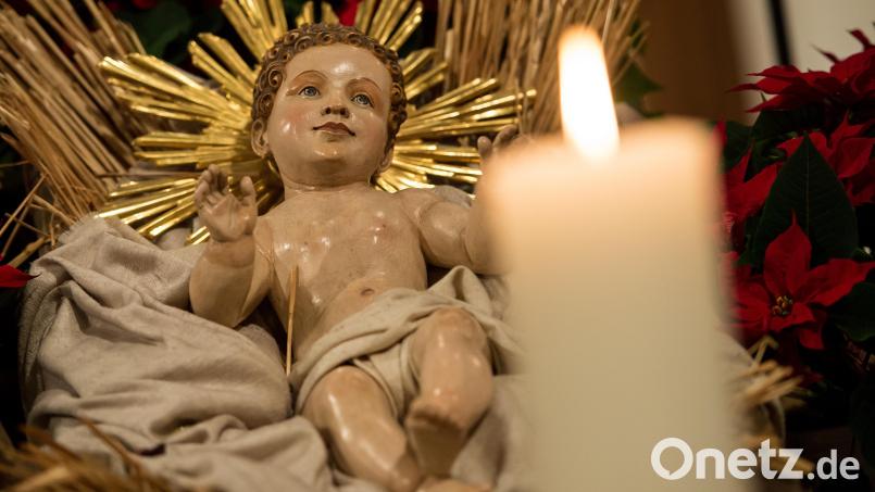 In einer Krippe liegt eine Holzfigur von Jesus. Daneben brennt eine Kerze. Bild: Sven Hoppe/dpa