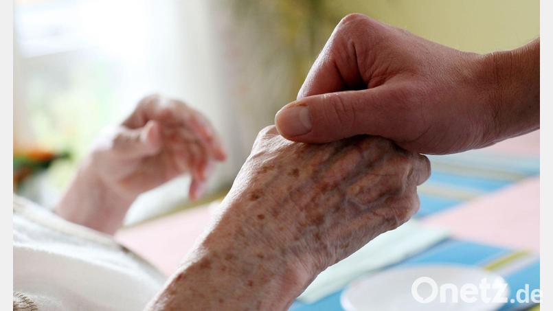 Ein Mitarbeiter eines Alten-und Pflegeheims hält die Hand einer Bewohnerin. (Archivbild) Bild: Oliver Berg/dpa