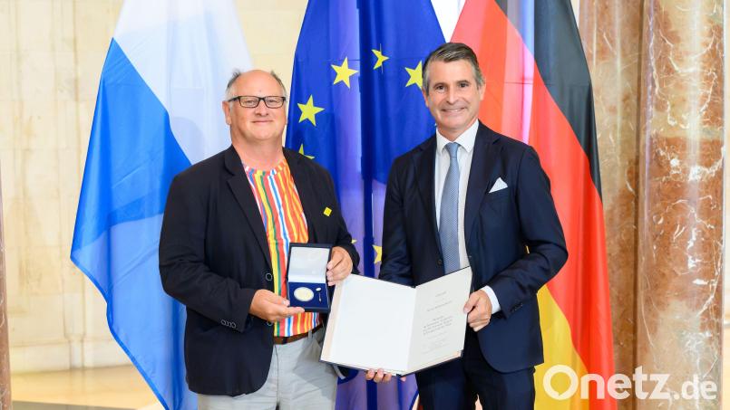 Wilhelm Koch (links) hatte sich für die Ehrung in München extra sein Europa-Hemd angezogen. Es trägt die Farben aller Flaggen der europäischen Länder. Minister Eric Beißwenger gratuliert. Bild: Joerg Koch/Bayerische Staatskanzlei