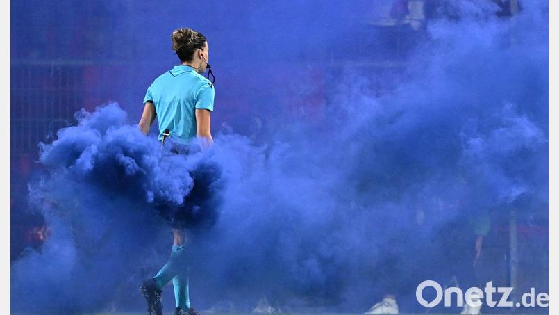 Schiedsrichterin Olatz Rivero Olmedo trägt den blauen Rauchtopf vom Spielfeld. Bild: Sven Hoppe/dpa