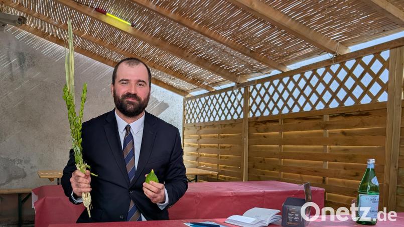 Florian Speil sitzt hier nicht einfach in einer Gartenlaube. Es ist ein Sukka, eine Laubhütte, die während des jüdischen Fest Sukot eine wichtige Rolle spielt. Sie darf nur vorübergehend und nur aus organischen Stoffen gebaut werden. In der Hand hält Speil Palmwedel und Früchte, denn Sukot ist auch ein Erntedankfest. Bild: wüw