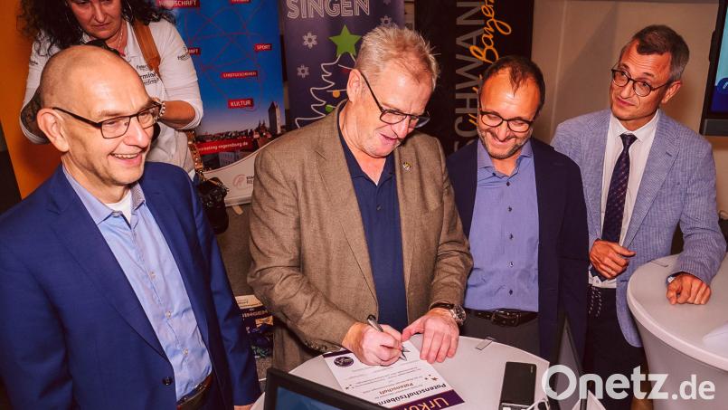 Schwandorfs Oberbürgermeister Andreas Feller (Zweiter von links) unterzeichnet die Vereinbarung für die Patenschaft der Stadt Schwandorf beim Regensburger Weihnachtssingen 2026. Foto: www.fotoschmiede-mcb.de
