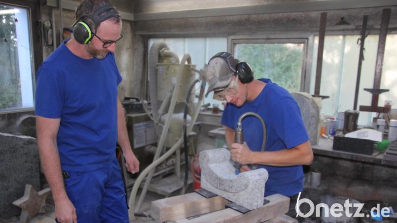 Christian Stöhr beim "Stocken", bei der Profilarbeit an einem Granitstein. Sein Meister, Johannes Kuchenreuther, schaut genau zu. Bild: Konrad Rosner