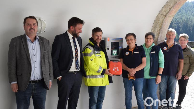 VR-Regionalleiter Fabian Diermeier (Zweiter von links) übergibt einen "Defi" an Bürgermeister Reinhard Schwarz (links) und Jugendherbergsleiterin Brigitte Ferner (Vierte von rechts). Thomas Zimmerer erklärt die Funktion. Bild: Richard Braun