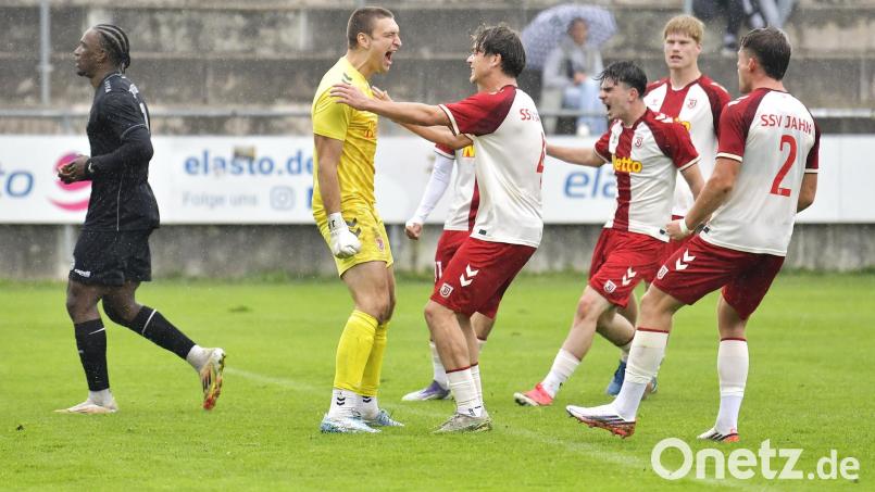 Jubel bei den Spielern des SSV Jahn Regensburg nach dem von Torhüter Julio Peutler gehaltenen Foulelfmeter, während der Gebenbacher Elfmeterschütze Jeanpaul Uzuamaka Ajala-Alexis (ganz links) enttäuscht davonschleicht.
DJK Gebenbach - SSV Jahn Regensburg II 1:6 Bild: Hubert Ziegler