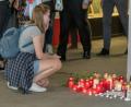 Eine junge Frau kniet neben Kerzen, Blumen und Fotos des getöteten Jugendlichen. Der 15-Jährige kam bei einer Schlägerei in der Passauer Innenstadt ums Leben.	Bild: Armin Weigel/dpa