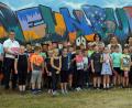 Bild: agr
Genauso bunt, wie die Graffitiwand am Schulgebäude, sind auch die Veranstaltungen im Ferienprogramm. Die neue Auflage präsentierten die Bürgermeister Albert Krieger (Bodenwöhr) und Martin Birner (Neunburg, von links) sowie Jugendbeauftragter Harald Klatzka, ArGe-Jugend-Vorsitzender Georg Keil, Schulleiterin Sabine Bauer und die Verwaltungsmitarbeiterinnen Martina Greiner und Elisabeth Lottner (von rechts), zusammen mit mehreren Kindern.