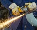 Bild:  Patrick Pleul/dpa-Zentralbild/dpa
Ein Arbeiter schleift mit einem Trennschneider an einem Rohr in einer Rohölverarbeitungsanlage. Arbeitnehmer im Osten arbeiten weiter länger als im Westen.