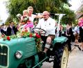 Bild: ds
Auf dem festlich geschmückten Traktor macht sich das frisch vermählte Brautpaar mit Töchterchen Antonia auf den Weg zum Kirchenreinbacher Gasthaus Goldene Krone, wo die Hochzeitsfeier ihre Fortsetzung nimmt.