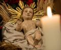 Bild: Sven Hoppe/dpa
In einer Krippe liegt eine Holzfigur von Jesus. Daneben brennt eine Kerze.