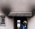 Bild: Lino Mirgeler
Ein Feuerwehrmann verlässt nach einem Brand ein Haus. Auf dem Dach über dem Eingang liegt ein angeschmortes Stofftier.