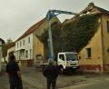 Bild: jml
Der Abriss beginnt. Von oben nach unten wird das alte Beer-Walbrunn-Geburtshaus entblättert. Die Kunstschiefer-Dachdeckung muss als Sondermüll behandelt werden und bei der imposanten Efeupflanze ist entblättern wörtlich zu nehmen. Karlheinz Meier, stellvertretender Vorsitzender des Kunst- und Kulturvereins Anton Beer- Walbrunn und ein großer Befürworter des Erhalts des Gebäudes (rechts), beobachtet das Geschehen.
