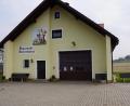 Bild: bkr
Nach rechts hin wird das Gerätehaus der Oberwappenöster Feuerwehr mit einem Schleppdach erweitert. Die grüne Fläche, auf der die Bank steht, nimmt den Anbau auf.