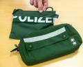 Bild: Daniel Karmann
Ein Brustbeutel und eine Fahrrad-Lenkertasche gefertigt aus Stoffen alter Polizei-Uniformen liegen auf einem Tisch.