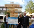 Bild: gis
Sprecherin Manuela Hornung und Christina Braun von der Ortsentwicklungsgruppe sowie zweiter Bürgermeister Karl Heinz Glaser (von links) präsentieren beim Dorffest den neuen Schilderbaum und die Infotafel zum 50. Breitengrad.
