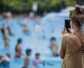 Bild: Jens Büttner/dpa
Eine junge Frau fotografiert im Schwimmbad mit ihrem Handy Kinder im Wasser.