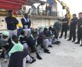 Bild: Annalisa Camilli/AP/dpa
Migranten vom Rettungsschiff "Sea-Watch 3" sitzen bewacht von Polizisten auf dem Steg im Hafen der Insel Lampedusa.