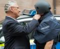Bild: Daniel Karmann/dpa
Der bayerische Innenminister Joachim Herrmann (CSU) hilft einem Polizisten mit Kugelsicherer Weste einen neuen ballistischen Schutzhelm zu schließen.