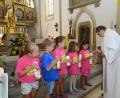 Bild: bey
Stadtpfarrer Pater Hans Ring zündet mit dem Licht der Osterkerze die Taufkerzen der Schulanfänger an, die diese dann vor dem Altar an ihrem Bild aufstellen.