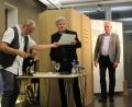 Bild: Dagmar Williamson, dwi
Friedrich Brandl (links) verteilt an Karl Krieg (Mitte) und Bernhard Setzwein (rechts) seine Notizen über das Jahr 1968. Professioneller Musiker Mike Reisinger trötet auf der Entenpfeife während er in seiner Jukebox-Attrappe, auch "Kabuff" genannt, verweilen muss.