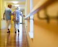 Bild: Christoph Schmidt/dpa
Eine Pflegekraft geht in einem Pflegeheim mit einer älteren Dame über einen Korridor.