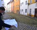 Bild: Hladik
Pfarrer Hans-Martin Meuß studiert den Plan. Der sieht vor, dass der Gehweg auf der Südseite von St. Michael (links zu sehen) verschwindet. Der Gehweg rechts entlang der Häuserzeile „Am Stock“ bleibt. Für die Anwohner werden – von der Schulgasse kommend – zwei Stellplätze zum Be- und Entladen eingerichtet.