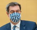 Bild: Peter Kneffel/dpa
München: Markus Söder (CSU), Ministerpräsident von Bayern, zieht sich für die Fotografen vor Beginn der Sitzung des bayerischen Landtags eine Mundschutzmaske auf.