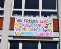 Bild: weu
Ein farbenfrohes Tuch, gefertigt von Sabine Lehner, mit der Aufschrift „Wir freuen uns auf ein Wiedersehen! Eure Lehrer“ hängt an der Außenwand der Grundschule und begrüßt die Schüler.
