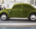 Bild: Julian Stratenschulte/dpa
Wie grün ist das E-Auto? Ein Ladekabel steckt in einem mit grünem Kunstrasen überzogenen VW Käfer.